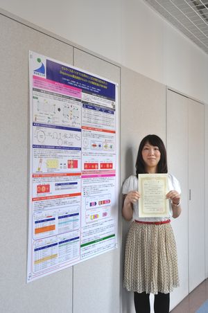 表彰状を手にする友常さんとポスター